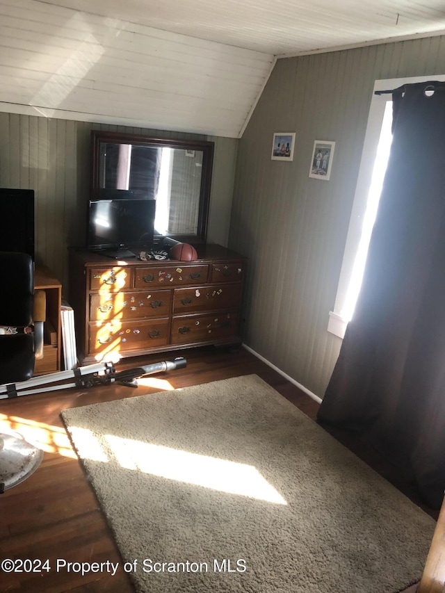 bedroom with dark hardwood / wood-style flooring, lofted ceiling, and wood walls