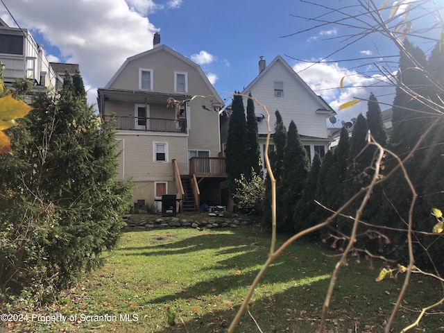 rear view of property featuring a yard, a balcony, and a deck