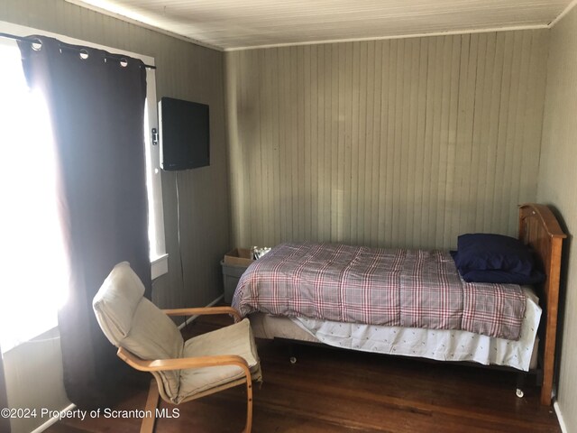 bedroom featuring dark hardwood / wood-style floors and wood walls