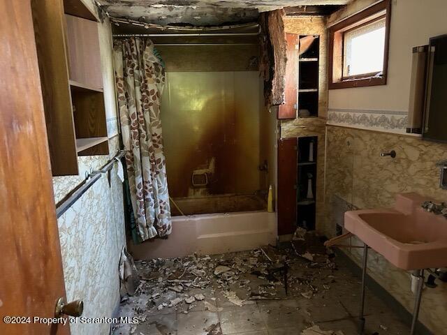 bathroom featuring shower / bath combo with shower curtain, tile walls, and sink