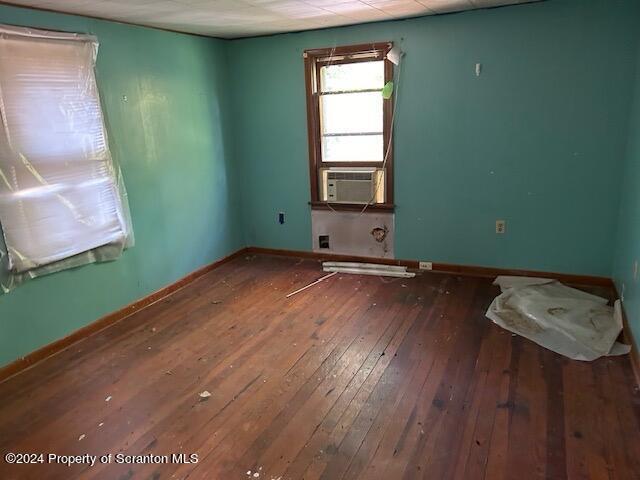 empty room featuring cooling unit and wood-type flooring