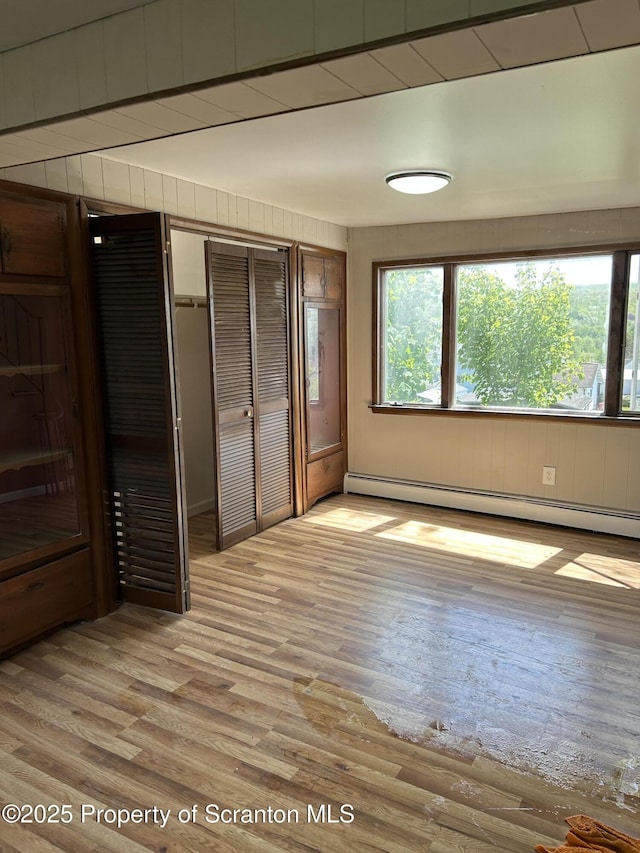 210 Gorham Ave, Mayfield, PA 18433 - unfurnished bedroom with a baseboard heating unit, light wood-style flooring, a closet, and wooden walls