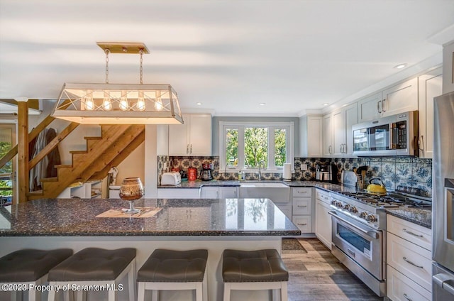 266 Warren Park Rd, New Milford, PA 18834 - kitchen featuring appliances with stainless steel finishes, a sink, a breakfast bar, tasteful backsplash, and dark stone countertops
