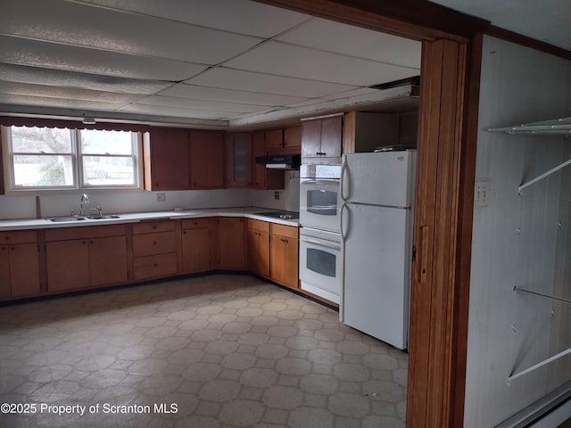 kitchen with under cabinet range hood, white appliances, a sink, light countertops, and light floors