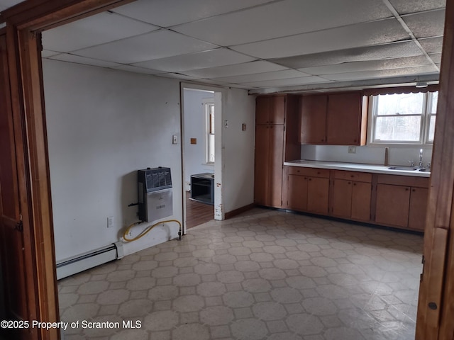 kitchen featuring a baseboard heating unit, light countertops, light floors, and a paneled ceiling