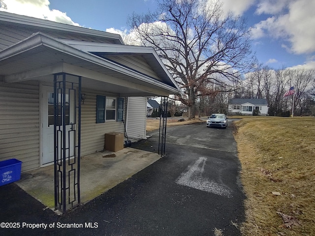 view of side of property featuring aphalt driveway and a lawn