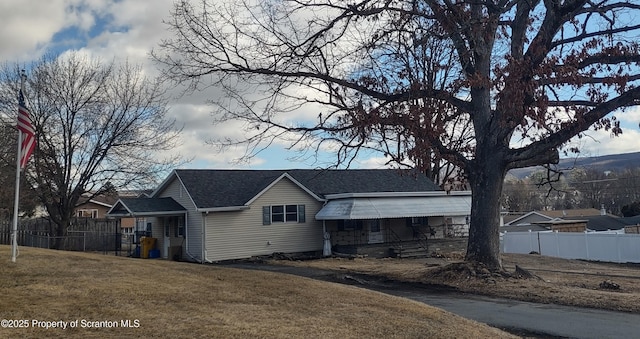 view of front of house with a porch, a front yard, roof with shingles, and fence