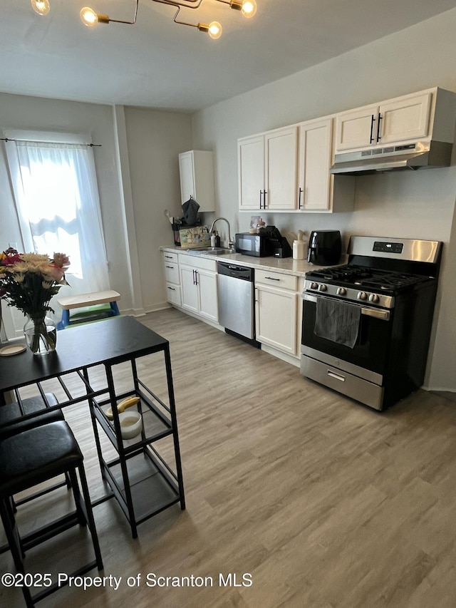 717719 Cedar Ave, Scranton, PA 18505 - kitchen featuring appliances with stainless steel finishes, a sink, under cabinet range hood, light wood finished floors, and white cabinets