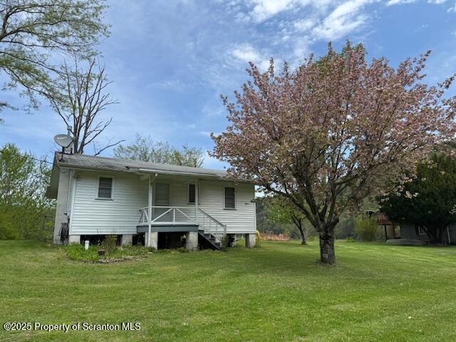 rear view of property with covered porch and a yard