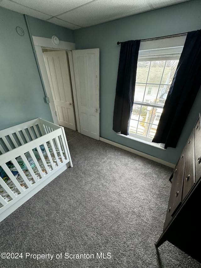 unfurnished bedroom with a drop ceiling and carpet