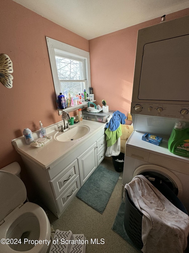 bathroom featuring stacked washer / drying machine, toilet, and vanity