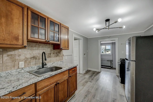 kitchen featuring decorative backsplash, appliances with stainless steel finishes, crown molding, light wood-type flooring, and a sink