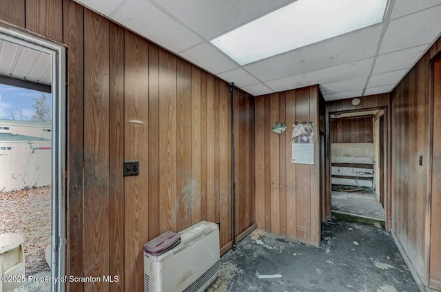 hall with wood walls and a drop ceiling