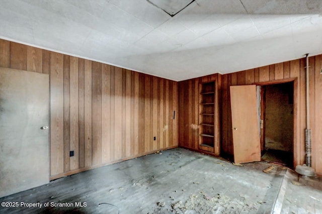 empty room featuring built in features and wooden walls