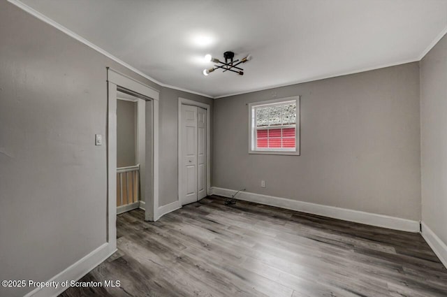 unfurnished bedroom featuring baseboards, crown molding, and wood finished floors