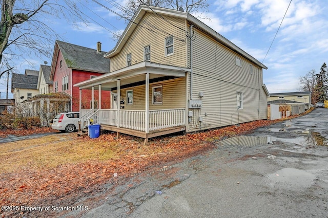 view of side of property featuring covered porch