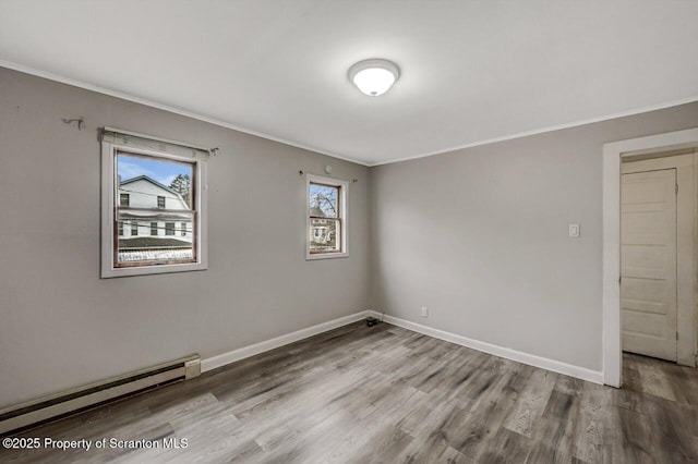 spare room featuring crown molding, a baseboard radiator, wood finished floors, and baseboards