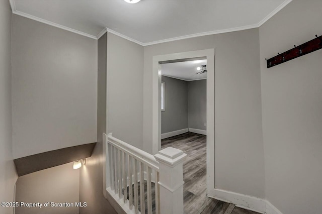 hall with ornamental molding, baseboards, and an upstairs landing