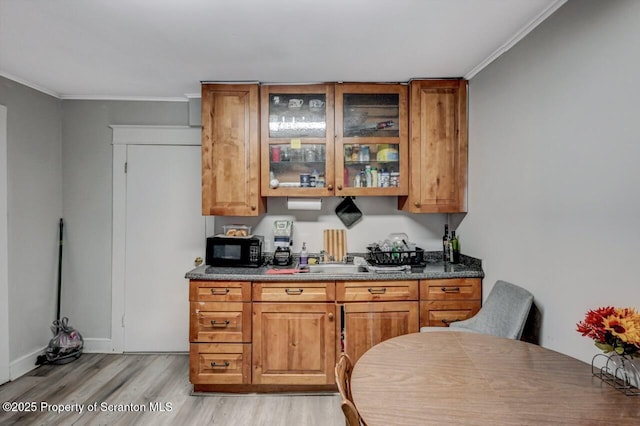 bar featuring black microwave, light wood finished floors, ornamental molding, and baseboards