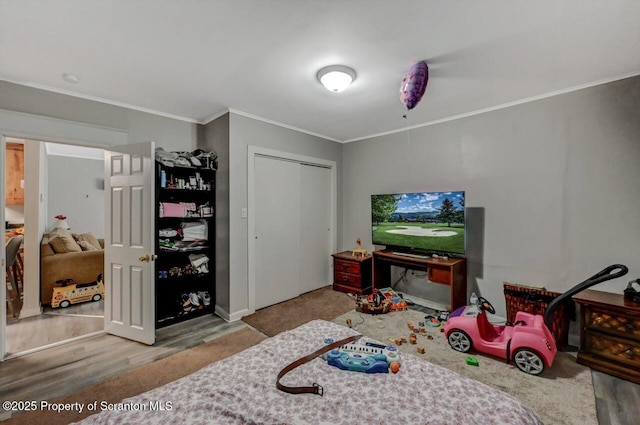 bedroom featuring ornamental molding, a closet, and wood finished floors