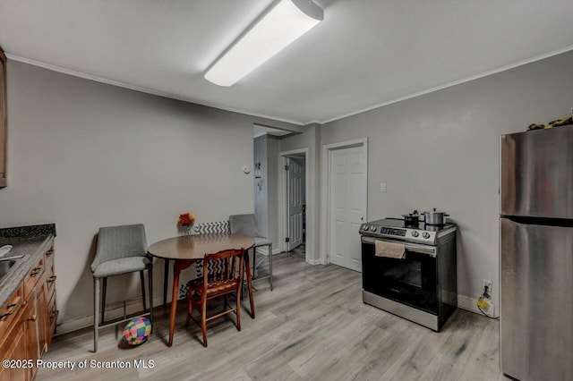 kitchen with appliances with stainless steel finishes, ornamental molding, light wood-style flooring, and baseboards