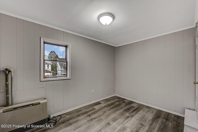 empty room with baseboards, ornamental molding, and wood finished floors