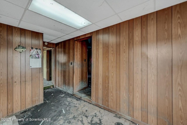 interior space featuring a paneled ceiling and wood walls