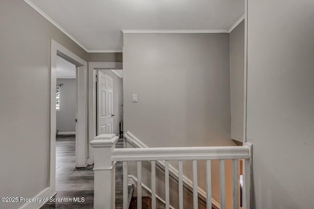 hall featuring baseboards, ornamental molding, wood finished floors, and an upstairs landing