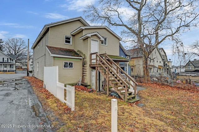 back of house featuring a residential view, fence, and stairway