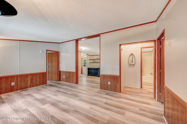 interior space featuring a textured ceiling, crown molding, and light hardwood / wood-style flooring