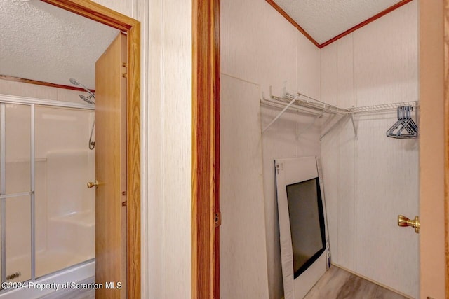 interior space featuring hardwood / wood-style flooring, a shower with shower door, and a textured ceiling