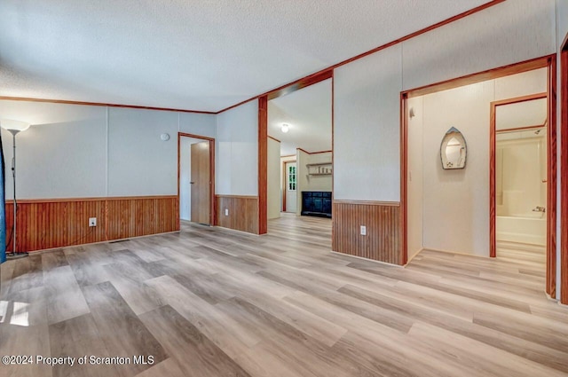 unfurnished living room featuring lofted ceiling, crown molding, a textured ceiling, and light wood-type flooring