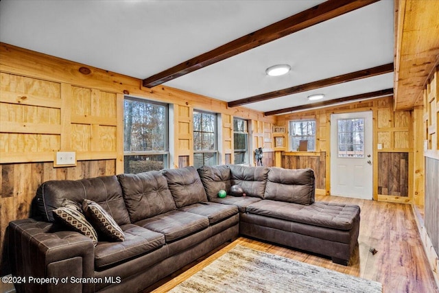 living room with beamed ceiling, light hardwood / wood-style floors, and wood walls