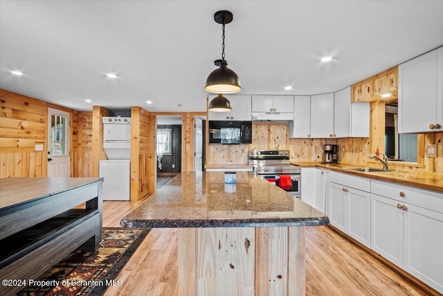 kitchen featuring white cabinetry, sink, pendant lighting, stacked washer / drying machine, and stainless steel electric range