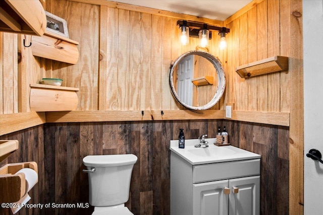 bathroom with vanity, toilet, and wooden walls