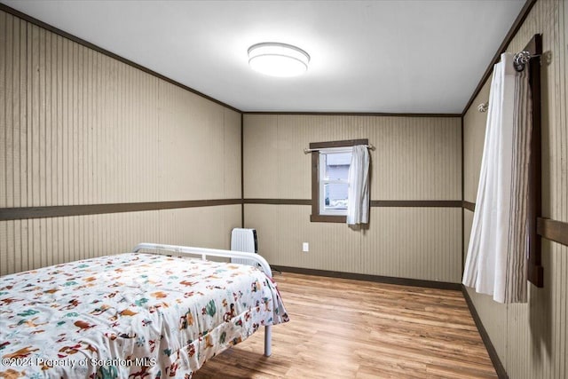 bedroom with wood-type flooring, radiator, and crown molding