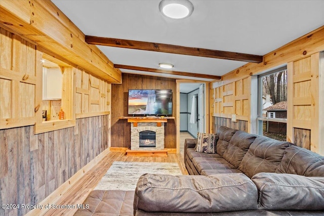 living room with beamed ceiling, wood walls, a stone fireplace, and hardwood / wood-style flooring