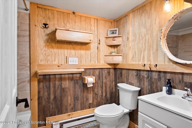 bathroom with baseboard heating, wood walls, vanity, and toilet