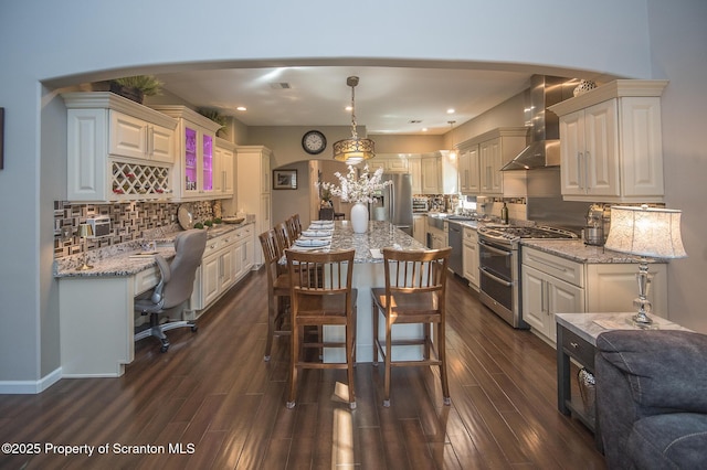 224 Shadow Wood Cir, Archbald, PA 18403 - kitchen featuring arched walkways, decorative backsplash, wall chimney exhaust hood, and stainless steel appliances
