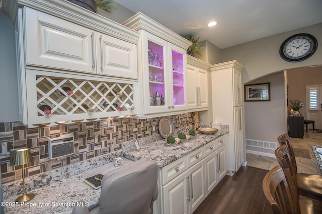 224 Shadow Wood Cir, Archbald, PA 18403 - kitchen featuring light stone counters, dark wood-style floors, visible vents, decorative backsplash, and arched walkways