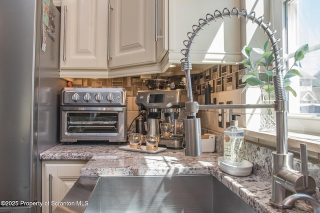224 Shadow Wood Cir, Archbald, PA 18403 - interior details featuring decorative backsplash, freestanding refrigerator, a toaster, and light stone countertops