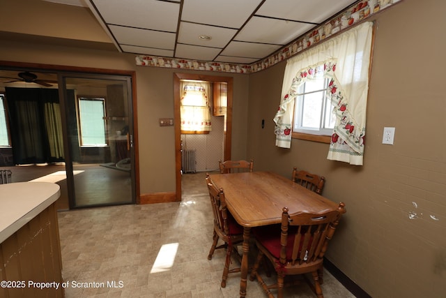 dining space featuring baseboards, a paneled ceiling, and radiator heating unit