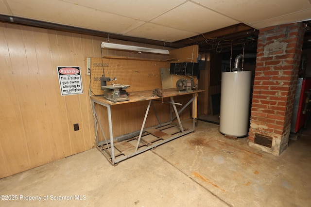 unfinished below grade area with gas water heater, a workshop area, and wood walls