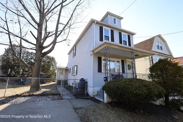 american foursquare style home featuring a porch and fence