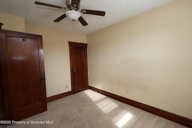 unfurnished bedroom featuring a ceiling fan, carpet, and baseboards