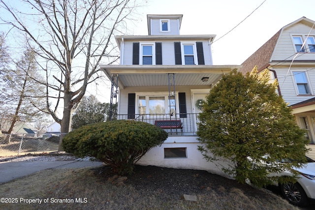 american foursquare style home featuring a porch and fence