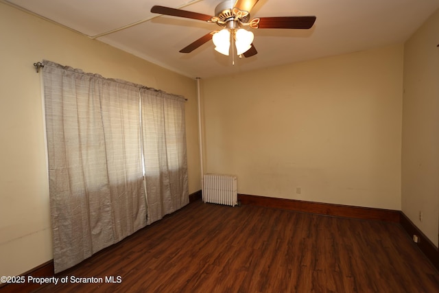 empty room with radiator, wood finished floors, baseboards, and ceiling fan