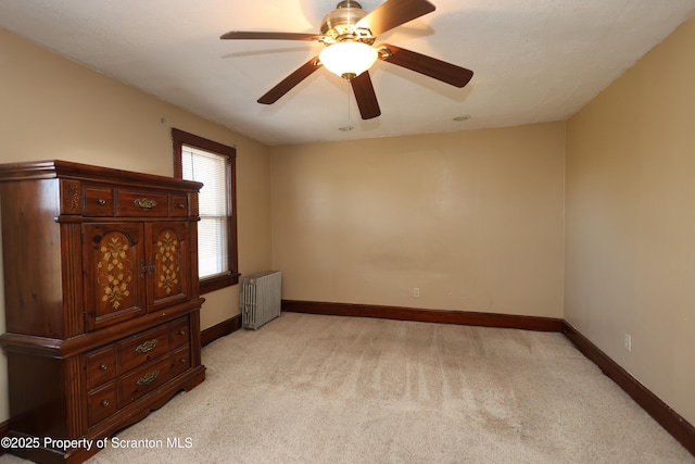 unfurnished bedroom featuring light colored carpet, baseboards, radiator, and ceiling fan