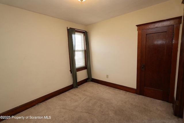 spare room featuring baseboards and light carpet