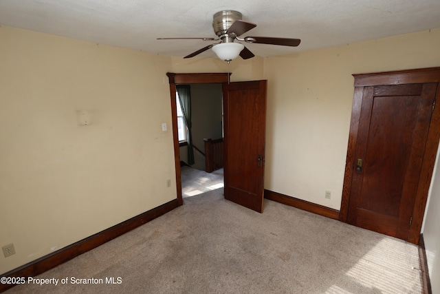 unfurnished bedroom with baseboards, carpet floors, and a ceiling fan